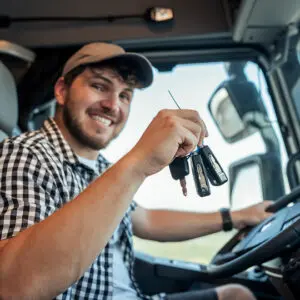 Smiling driver holding keys inside truck.