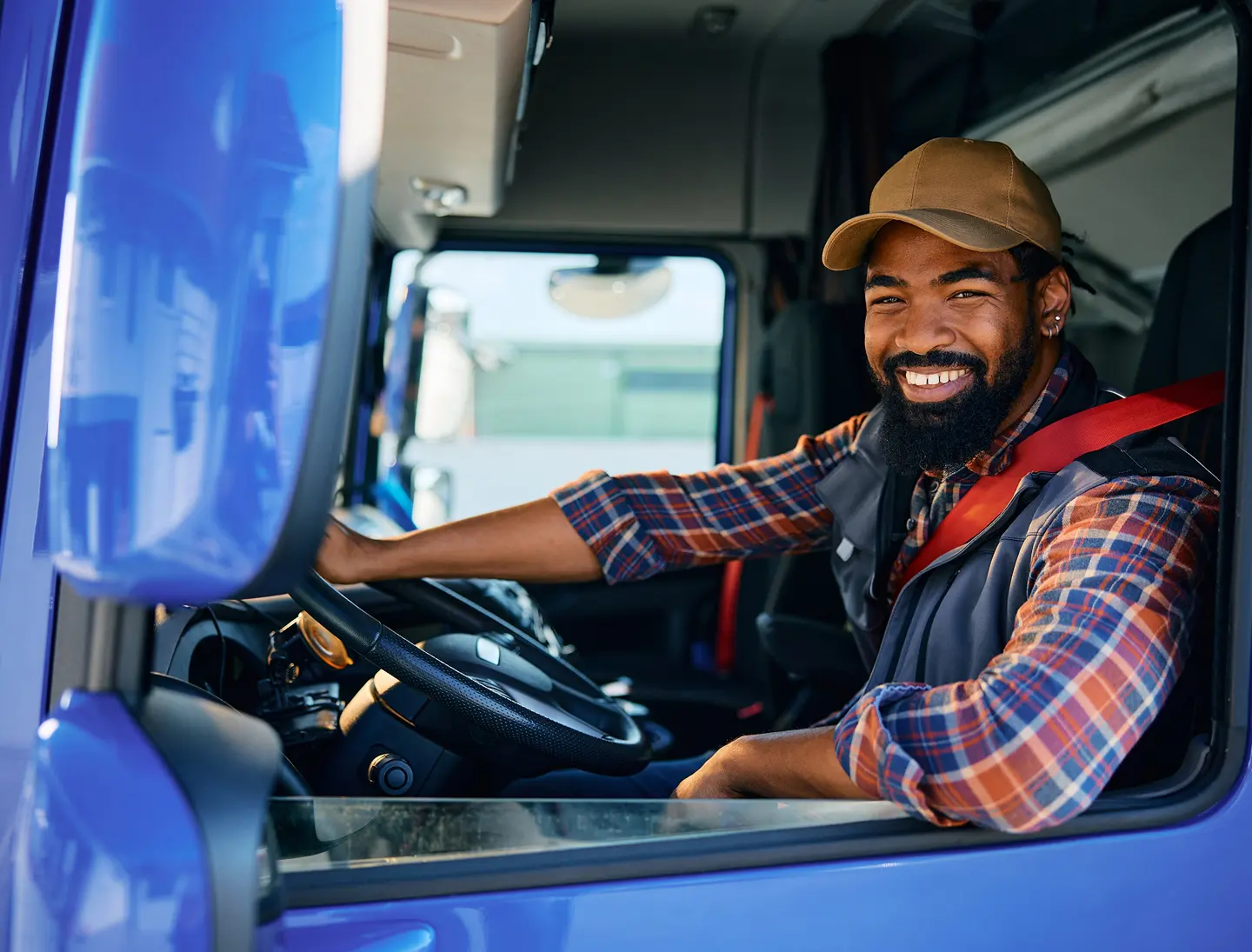 Truck driver smiling inside vehicle cabin.